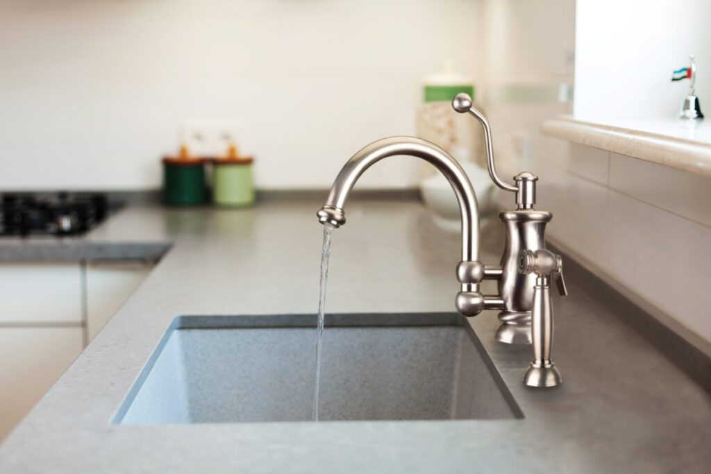 Modern designer chrome water tap over stainless steel kitchen sink.